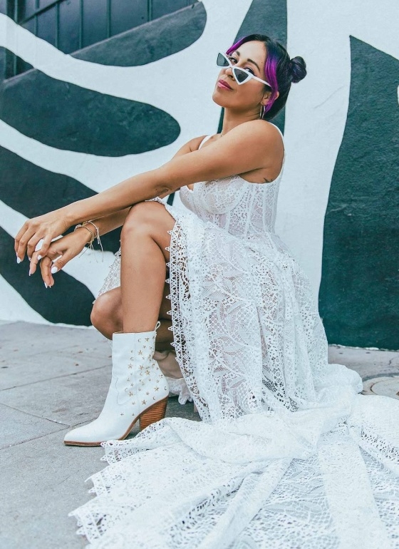 Photo of the model wearing a bridal gown and sitting near the wall
